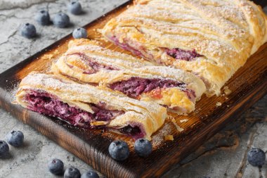 Taze böğürtlenli lezzetli yaban mersinli turta ve masanın üzerindeki ahşap tahtaya yakın plan krema. Yatay