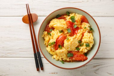 Kanton usulü domates yumurtası çırpılmış ve ahşap masadaki tabakta yeşil soğan yakın plan. Yukarıdan yatay üst görünüm