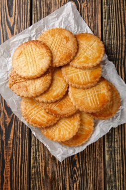 Sable Breton, Bretagne bölgesinden gelen klasik bir tereyağlı kurabiyedir. Tahta masadaki parşömen kağıdına yakın plan. Yukarıdan dikey üst görünüm