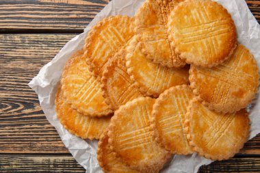 Lezzetli Fransız kurabiyesi Sable Breton ahşap masadaki parşömen kağıdına yakın plan. Yukarıdan yatay üst görünüm