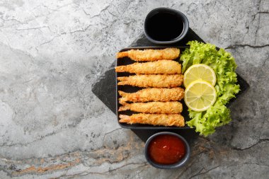 Japon kral karidesleri tempura limon, marul ve iki sosla servis edilir. Yukarıdan yatay üst görünüm