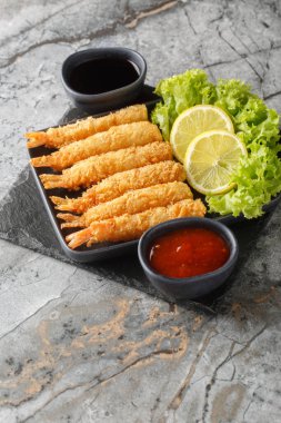 Limon dilimleri ve soslarla servis edilen leziz kızarmış karidesler masanın üstünde. Dikey