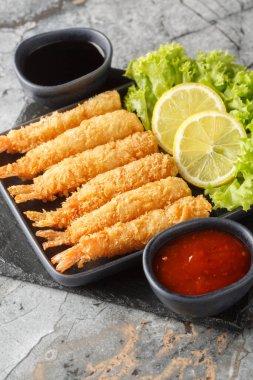 Japon usulü çıtır tempura karidesli ev yapımı tempura vurucu masadaki tabağa yakın çekim. Dikey