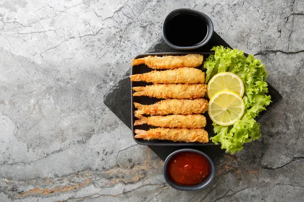 Japon kral karidesleri tempura limon, marul ve iki sosla servis edilir. Yukarıdan yatay üst görünüm
