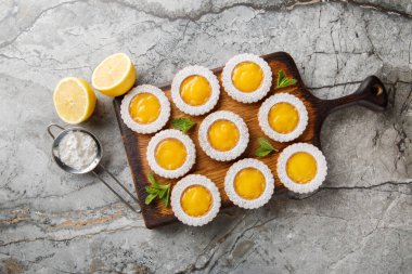 Ev yapımı limonlu kurabiye, çiçek şeklinde, masanın üzerindeki tahta tahtaya yakın plan şeker serpiştirilmiş. Yukarıdan yatay üst görünüm