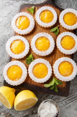 Kurabiyeler iki kat tereyağlı Shortbread Kurabiyesi ve masadaki ahşap tahtada yakın plan dolduran ev yapımı ekşi limonlu kremayı birleştirir. Yukarıdan dikey üst görünüm