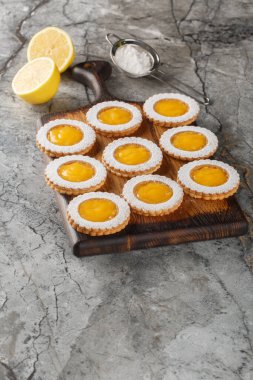 Kurabiyeler iki kat tereyağlı Shortbread Kurabiyesi ve masadaki ahşap tahtada yakın plan dolduran ev yapımı ekşi limonlu kremayı birleştirir. Dikey