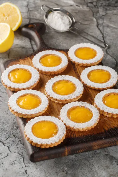 Lezzetli tatlı limonlu krakerler üzerine pudra şekeri serpiştirilmiş tahta tahtaya yakın plan. Dikey