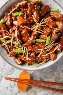 Kızarmış biftekli zencefilli biftek, hafif tatlı bir sos, yeşil soğan ve masanın üzerindeki kasede zencefilli kurabiye. Yukarıdan dikey üst görünüm