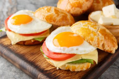 Lezzetli ananaslı çörekler ya da kızarmış yumurta, tereyağı, domates, peynir, marul yakın plan ahşap masa. Yatay