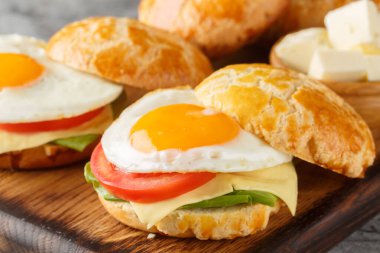 Ananaslı çörekten yapılmış taze Hong Kong sandviçleri, kızarmış yumurta, tereyağı, domates, ahşap tahtada yakın plan peynir. yatay