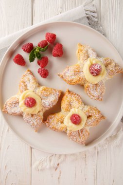 Krema ve taze ahudududulu bir çiçek şeklinde poğaça keki masanın üstünde. Yukarıdan dikey üst görünüm