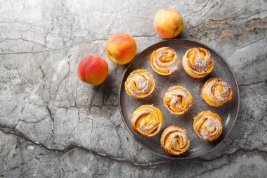 Şeftali gülleri mini tartlar pudra şekerli pudra şekerli poğaçalardan yapılmış çörekler masanın üzerinde. Yukarıdan yatay üst görünüm