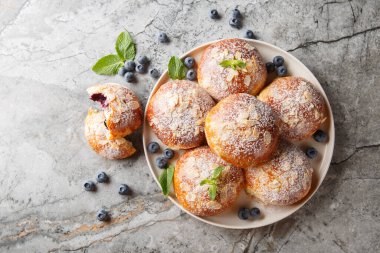 Böğürtlenli maya çörekleri, badem yaprakları ve masadaki tabakta yakın plan şeker. Yukarıdan yatay üst görünüm