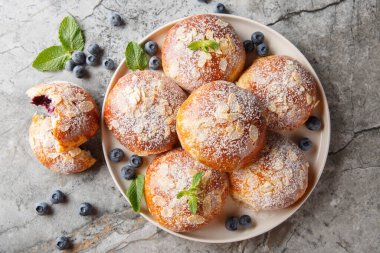 Taze yaban mersinli çörekler, badem yaprakları ve masanın üstünde yakın plan şeker tozu. Yukarıdan yatay üst görünüm