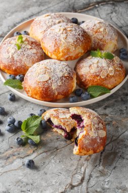 Masanın üzerindeki tabakta mercimeği fırına vermiş taze bademli çörekler. Dikey