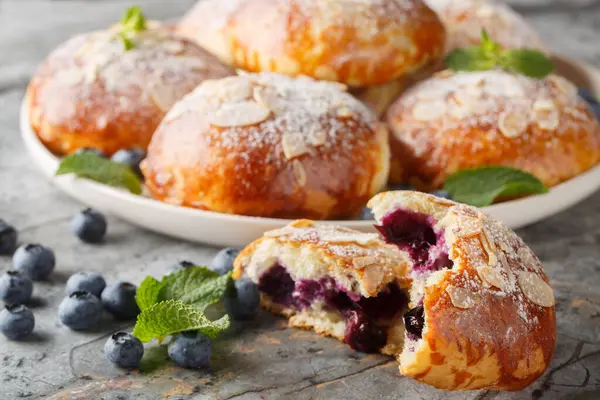 Brioche çörekleri, yaban mersini, badem gevreği ve pudra şekerini masaya yakın plan çek. Yatay