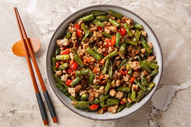 Yeşil fasulyeli çıtır domuz kızartması, sarımsak ve dolmalık biber masadaki kaseye yakın çekim. Yukarıdan yatay üst görünüm