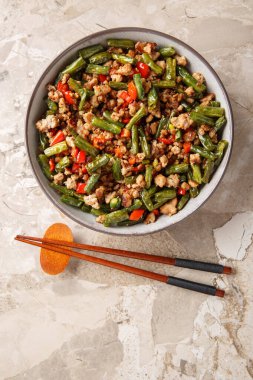 Kızarmış Çin fasulyesini gevrek domuz eti, dolma biber, sarımsak ve zencefil ile karıştırın. Yukarıdan dikey üst görünüm