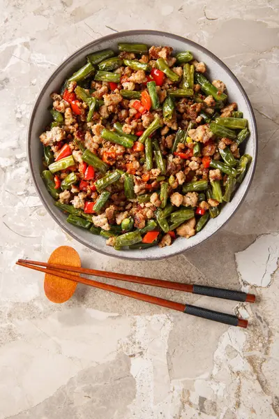 Kızarmış Çin fasulyesini gevrek domuz eti, dolma biber, sarımsak ve zencefil ile karıştırın. Yukarıdan dikey üst görünüm