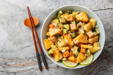 Asya Rojak meyve sebze salatası tofu peyniri ile tatlandırılmış tatlı ve baharatlı sos yakın plan bir kasede masada. Yukarıdan yatay üst görünüm