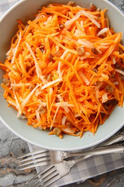 Kremalı ve çıtır çıtır havuçlu elma üzümlü salatayı yakın plan bir kasede masanın üstünde. Yukarıdan dikey üst görünüm