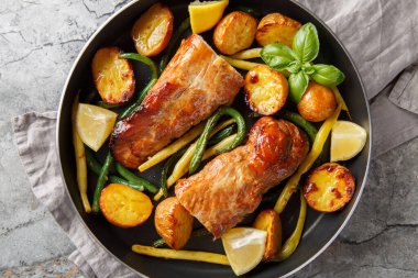 Fransız fasulyeli limonlu sarımsaklı domuz rostosu ve masada yeni patatesler. Yukarıdan yatay üst görünüm