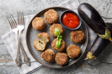 Masadaki tabakta domates sosuyla servis edilen leziz kızarmış patlıcanlı börekler. Yukarıdan yatay üst görünüm