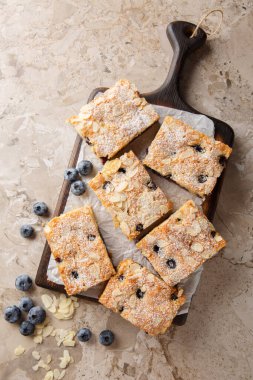 Böğürtlenli bademli pandispanya ve pudra şekeri masadaki tahtaya yakın plan. Yukarıdan dikey üst görünüm