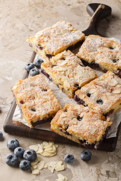 Yumuşak ve nemli yaban mersinli bademli kek masadaki tahta tahtaya yakın plan. Dikey