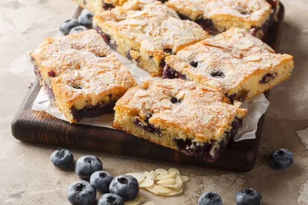 Yaban mersinli kahvaltı keki taze böğürtlenlerle dolup taşıyor ve üzerine de masadaki tahta tahtaya yakın kıymık dilimlenmiş bademler konuyor. Yatay