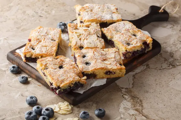 Böğürtlenli yaban mersinli badem keki. Masanın üzerindeki tahta tahtaya yakın plan şekerli. yatay