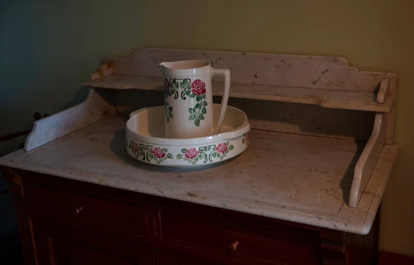old chest of drawers with porcelain water pitcher and basin