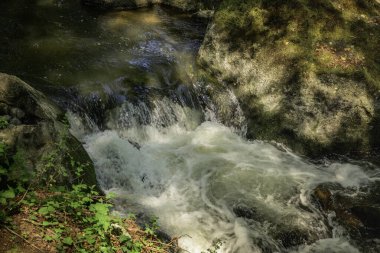 Almanya 'daki Rauscherpark' ta, Maria Laach yakınlarında büyük kayaların arasında küçük bir şelale.