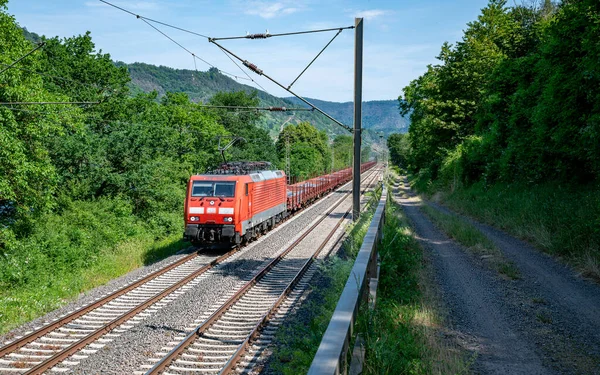 Czerwony Pociąg Towarowy Kilkoma Pustymi Wagonami Przejeżdża Przez Niemiecki Krajobraz — Zdjęcie stockowe