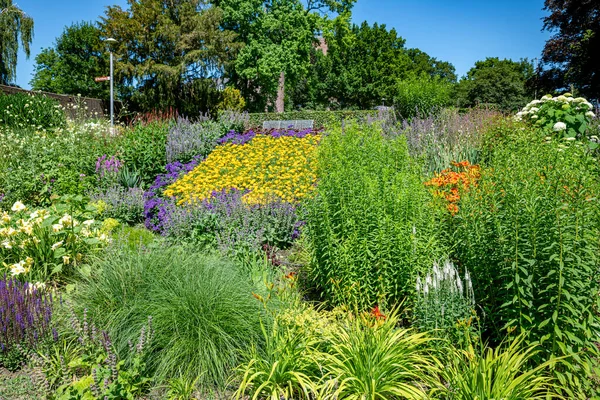緑の木々や花が紫色のオレンジ黄色で装飾的な標高のある芝生と境界線の美しい英語の庭 — ストック写真