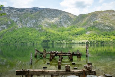 Slovenya, Triglav Ulusal Parkı 'ndaki Bohinj Gölü' nde eski bir ahşap iskelenin, dağların ve güzel doğanın kalıntıları.