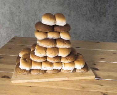 Şeffaf arkaplanı olan ahşap bir masada beyaz ve kahverengi rulo yığını.