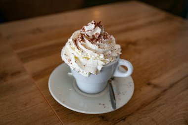 Büyük bir fincan kapuçino. Bol kremalı ve çikolatalı. Bir restoranda bir fincanda servis ediliyor.