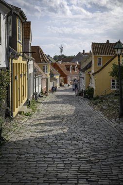 ebeltoft, Danimarka, 30-08-2024: Mavi gökyüzü altında canlı binaların ve kaldırım taşlarının yer aldığı antika Avrupa caddesi. Huzurlu bir atmosfer, keşif için mükemmel.