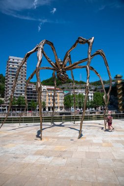 Bilbao, İspanya, 18-05-2025: Bilbao, İspanya 'da bir bahar günü Louise Bourgeoison tarafından yapılan ünlü örümceğin yanında yürüyen insanlar.
