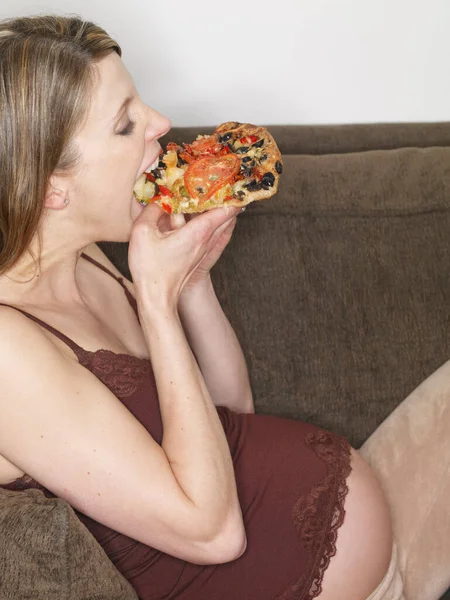 Беременная Женщина Ест Пиццу Лежит Диване — стоковое фото