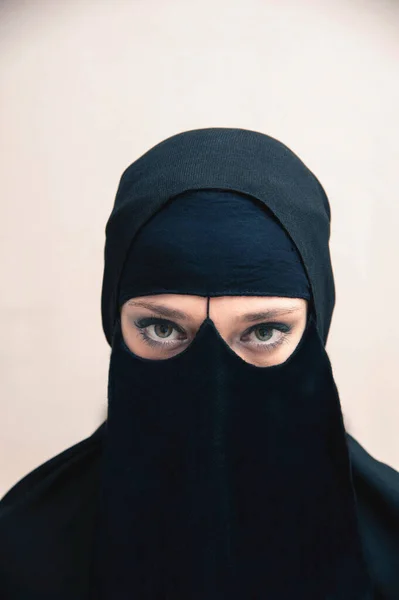 身穿黑色 穆斯林头巾和穆斯林服装的年轻女子的特写肖像 眼睛看着显示眼睛妆容的相机 工作室拍摄的白色背景 — 图库照片
