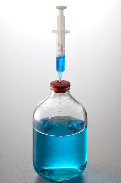 蓝色液体罐子里的针 — 图库照片
