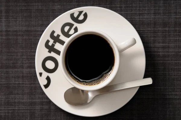 スプーンでソーサーにブラックコーヒーのカップのオーバーヘッドビュー — ストック写真