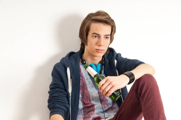Adolescente Niño Usando Auriculares Alrededor Del Cuello Sosteniendo Botella Cerveza — Foto de Stock