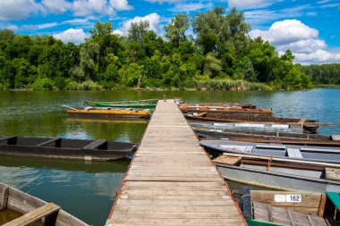 Martly 'deki Tisza Nehri' nin durgun sularında rıhtım ve tekneler.