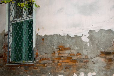 İhmal edilmiş tuğla duvar ve çökmüş alçılı bir evin penceresi.