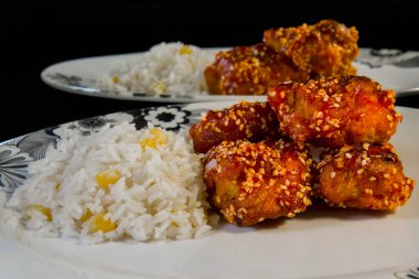 Crispy sesame chicken with rice on a white plate