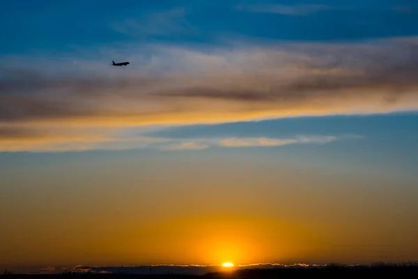 飛行機は日没時に空を飛んでいる — ストック写真